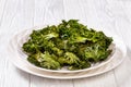 White plate with kale chips on the table Royalty Free Stock Photo