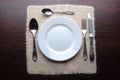 White plate, knife, fork and spoons at napkin on wooden backgrou Royalty Free Stock Photo