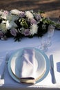 White plate with light violet napkin, clearwine glass and florals - lilis, roses and chrysanthemum. Wedding reception table