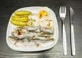 White plate with marinated herring in oil, boiled hard-boiled egg, cucumber and mayonnaise. Seasoned with pepper and paprika.