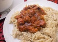 A white plate of mashed pasta served with meat sauce