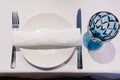 white plate with napkin and cutlery, beautiful blue glass wine glass on table. Royalty Free Stock Photo