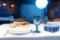 white plate with napkin and cutlery, beautiful blue glass wine glass on table. Royalty Free Stock Photo