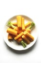 White plate of peeled orange carrots green leaves