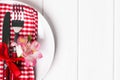 White plate with red napkin, fork, knife and little flower close-up Royalty Free Stock Photo