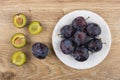 White plate with ripe plums and half of plums Royalty Free Stock Photo