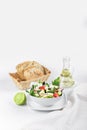 White plate with salad on the background of a bottle of butter, toast and lime.