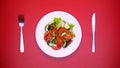 White plate with salad and cutlery red background, table setting restaurant Royalty Free Stock Photo