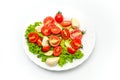 White plate of salad with vegetables on white background. Top view. Tomato, pepper, salad, garlic