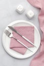 White plate with silver cutlery. Knife, fork and pink napkin on grey background. Table setting, flat lay, top view. Serving space Royalty Free Stock Photo