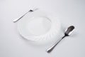 A white plate with silver fork and spoon isolated on white background with copy space. Dinner place setting. Table Setting. Royalty Free Stock Photo