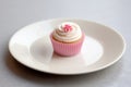 a white plate with a single tiny pink cupcake Royalty Free Stock Photo