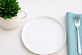 White plate sits on a table with a fork and a napkin Royalty Free Stock Photo