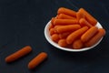White plate with small peeled pieces of carrot on dark textured background