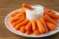 White plate with small peeled pieces of carrot and sauce on textured wooden table