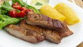 White plate with smoked pork meat accompanied by fried yucca and lettuce and tomato salad Royalty Free Stock Photo