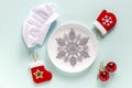 White plate with snowflake, chef cap and new year decorations around.