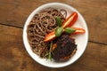 White plate soba with chicken tomatoes and spinach on the table.