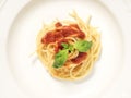 White plate, spaghetti top view, with red tomato sauce and green basil leaves on top Royalty Free Stock Photo