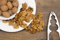 A white plate of walnut kernel and a whole nut on wooden table Royalty Free Stock Photo