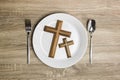 A white plate with a wooden cross and Bible over the wooden table. Royalty Free Stock Photo