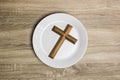 A white plate with a wooden cross and Bible over the wooden table. Royalty Free Stock Photo