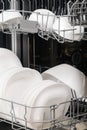 White plates and cups in the dishwasher compartment, close-up, side view Royalty Free Stock Photo