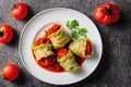 White plates with portion of stuffed cabbage rolls in bright tomato sauce