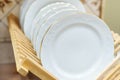 White plates on a wooden stand. Kitchen utensils close up Royalty Free Stock Photo