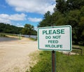 White please do not feed wildlife sign with dirt trail and water Royalty Free Stock Photo