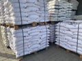 White polypropylene large bags with building materials or bulk materials lie on top of each other on wooden pallets in an