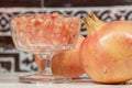 White pomegranate grains on crystal goblet, beside fruits