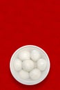 A white porcelain bowl of rice balls is placed on a traditional auspicious cloud, plum, and wooden board texture background.