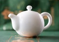 White porcelain Chinese teapot on a green background