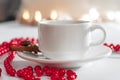 White porcelain cup. Cinnamon stick. Blurred circles bokeh. red decor