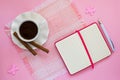 White porcelain cup with coffee, two coffee rolls on saucer with wavy edge and paper notebook with ball pen on a pink table napkin Royalty Free Stock Photo