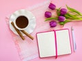 Porcelain cup with coffee and two coffee rols on saucer with wavy edge, paper notebook with ball pen and bouquet of pink tulips on Royalty Free Stock Photo