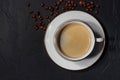 White porcelain espresso cup surrounded by coffee beans on a black handmade background in loft or grunge style. Royalty Free Stock Photo