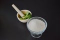 A white porcelain mortar and pestle, fresh green mint leaves, glass cup full of sugar, black background Royalty Free Stock Photo