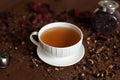 White porcelain mug on a saucer with herbal tea on a brown background Royalty Free Stock Photo