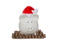 White porcelain piggy bank wearing santa hat with stacked coins Royalty Free Stock Photo