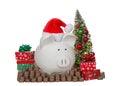 White porcelain piggy bank wearing santa hat with stacks of coins and xmas decorations Royalty Free Stock Photo