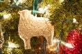 A white porcelain sheep folk art ornament on a Christmas tree.