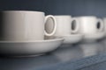 white porcelain teacups and saucers stand on a shelf with a wooden texture in blue-gray close-up Royalty Free Stock Photo