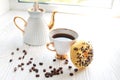 white porcelain teapot and cup on white wooden table on windowsill on sunny day. Tea after game. Chess pieces near coffee beans. Royalty Free Stock Photo