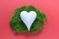 White porcelein heart on green moss on pink