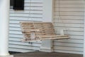 White porch swing on slatted or panneled wooden house patio and plantation poles or beams near front door in yard Royalty Free Stock Photo