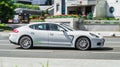 White Porsche Panamera on the city road. Fast moving car on the street. Vehicle driving along the street in city with blurred