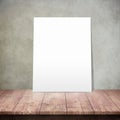 White poster on a wooden table with concrete wall background Royalty Free Stock Photo