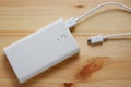 White power bank or backup battery with USB 2.0 cable charger on wooden background.Top view